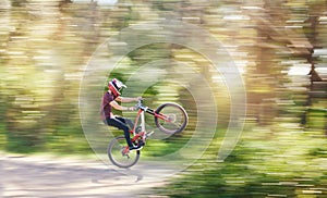 Blur, air and man cycling in nature training for a competition on trail or path in forest or woods. Freedom, stunt or