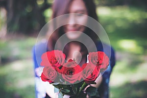 Blur Asian women giving red roses flower to her boyfriend on Valentine`s day