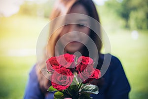 Blur Asian women giving red roses flower to her boyfriend on Valentine`s day