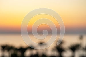 Blur background of silhouette of palm trees of sea beach against the backdrop of  setting sun on sunset sky. Top view. Panoramic.