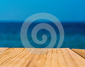 The blur blue sea background with wood floor foreground, relaxing outdoors vacation with paradise view at a resort deck touching