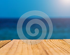 The blur blue sea background with wood floor foreground, relaxing outdoors vacation with paradise view at a resort deck touching