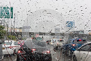 Blur city life through windshield : Drops of rain on car`s mirro