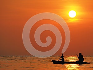 Blur defocus beautiful orange sky sunset above the sea with silhouette of man and boy paddle kayak in sea at Koh Kood, Thailand.