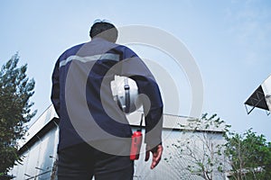 Blur foreground image of asian engineer in safety uniform holding white security helmet and walkie-talkie against industry plant