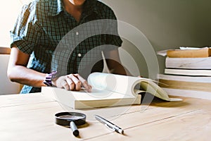 Blur. Man in green plaid shirt.Sitting on wood chair, reading book.