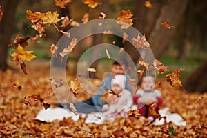 Blur photo of happy family of three kids at autumn leaves park