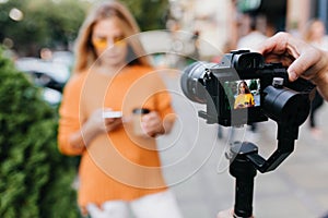 Blur portrait of girl in yellow glasses with black camera in focus. Outdoor photo of female model in bright outfit with