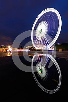 Blur rotate moving of Ferris wheel with lighting reflection on water