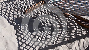 Blur shadows of swinging net hammock and child silhouette on beach sand