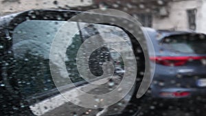 Blur side mirror view with drops of rain. Rainy weather while driving by road with bumps and pits