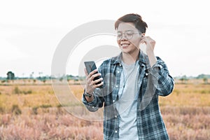 Blur soft-focus smiling Asian young man listening to the podcast is a music audio mp3 player on smartphone outdoors nature sunset