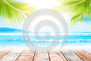 Blur tropical beach with bokeh sun light wave and palm tree on empty old wood table abstract background