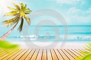 Blur tropical beach with bokeh sun light wave and palm tree on empty old wood table abstract background