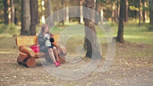 Blur A woman with brown hair in red boots and a red bag on a park bench in autumn speaks by phone