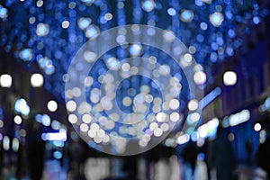 Blurred abstract background, bokeh in night street with festive lights and walking people