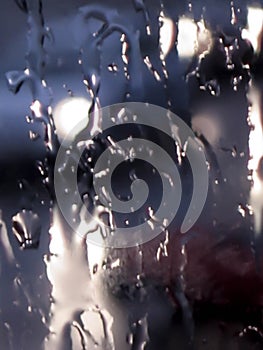 Blurred abstract moody defocused close-up background of bad weather raindrops splashing against a wet transparent glass window