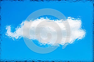 Blurred abstract natural background. Abstract image of a white cloud on a blue sky through wet glass. Water drops