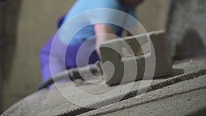 Blurred adult Caucasian man in uniform taking hammer and adjusting equipment on concrete manufacturing site. Male worker