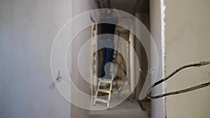 Blurred adult male electrician on ladder covering cables to install lamp while home improvement. Renovation of apartment