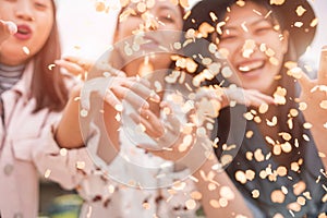 Blurred asian friends having fun throwing confetti at party outdoor - Young trendy people enjoying fest event - Hangout,