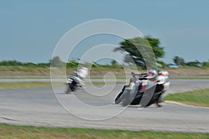 Blurred athletes practicing racing motorcycles on the race track