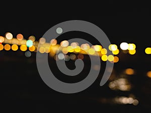 The blurred background of city river bridge at night with bokeh lights.