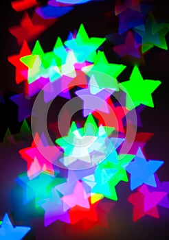 Blurred background with colorful bokeh star shaped lights on dar