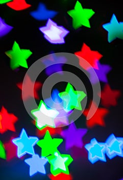 Blurred background with colorful bokeh star shaped lights on dar