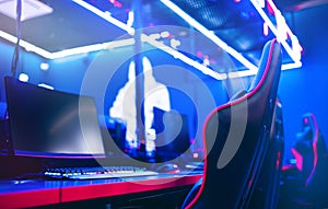 Blurred background computer pc, keyboard armchair, blue and red lights. Concept online eSports arena for gamer playing photo