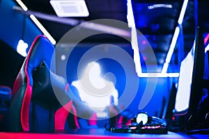 Blurred background computer pc, keyboard armchair, blue and red lights. Concept online stream eSports arena for gamer