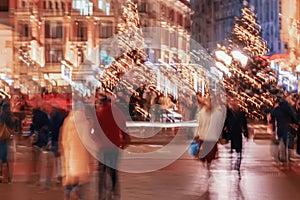 Blurred background of crowd of people on city streets, Christmas holidays. Evening, illuminated streets, neon lights