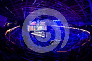 Blurred background of an esports event - Big illuminated main stage of a computer games tournament located on a big