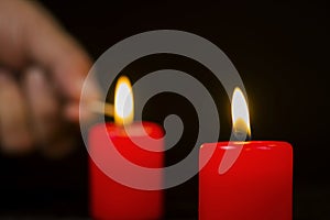 Blurred in the background a hand lighting candles