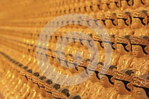 Blurred background image of wall in ancient asian buddhist temple with umpteen small golden Buddha statues.