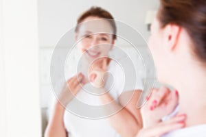 Blurred background of Middle age woman looking in mirror on face. Wrinkles and anti aging skin care concept. Selective focus