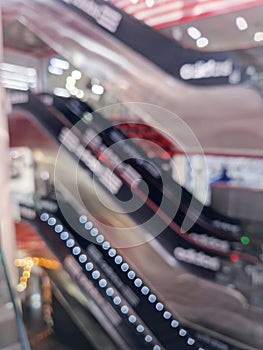 Blurred background with people in motion on escalators inside a modern shopping mall. Defocused commercial center indoors view