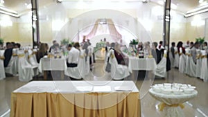 Blurred background, people sitting at the dinner table. Waiters serve, people in the background are blurred.