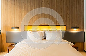 Blurred background, A queen-size bed covered with a white duvet and four pillows placed on the bed. the room decorated