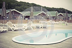 Blurred background recreation base wooden houses pool sunbeds wooden floor hill forest trees sky toning.