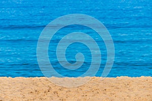 Blurred background sea. Abstract summer background. Glare of the sun against the sea, beautiful bokeh. Yellow sand on the beach