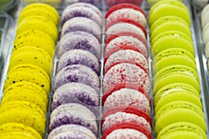 Blurred background showcase pastry shop. Smooth rows of cookies, cakes, yellow red purple white macarons on the counter of