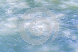 Blurred background with the surface of a fast flowing mountain river.
