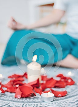 Blurred background of woman practicing yoga in front of candles and rose petal