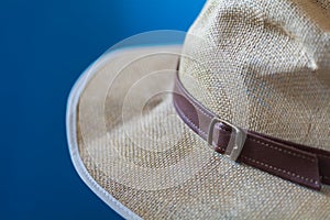 Blurred blue image of a cream hat with white fringe and brown strap photo