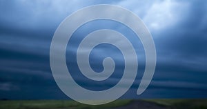 Blurred blue stormy clouds with lightnings float in sky over fields