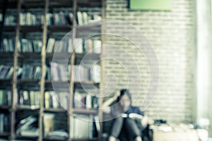 Blurred books on the shelf with people is reading a book