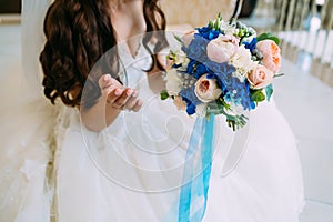 Blurred Bride holds bouquet with creamy roses and peonies and blue hydrangeas. Wedding morning. Close-up
