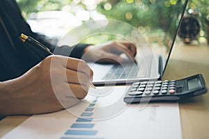 Blurred of a businessman writing on charts paper at workstation. Modern business man writing on chart paper and using laptop