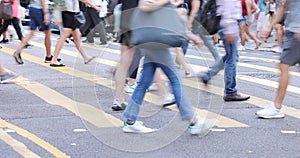 Blurred Busy crowds of men and women or Commuters Crossing Street in Central, Hong Kong, with Crosswalk yellow lines. zebra yellow